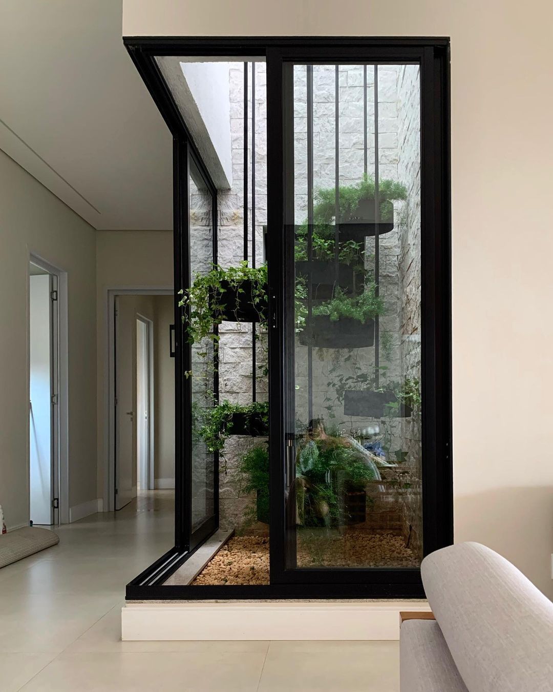 Mampara corrediza de dos hojas hacia un jardín vertical interior